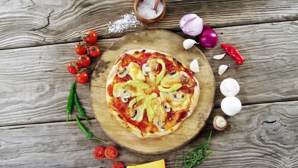 Italian pizza on wooden table with vegetables and spices