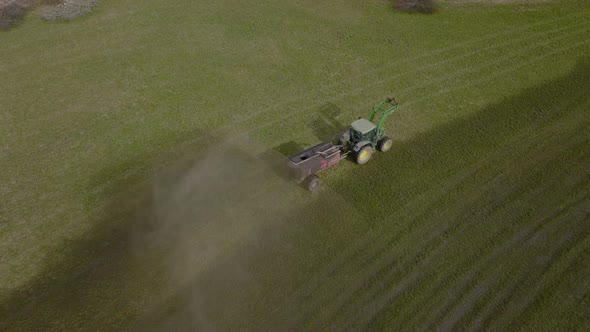 Crop farming scene of tractor spraying field. Fertalization by agricultural machinery - drone shot