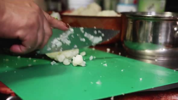 Vegan chef chopping fresh cauliflower on a green cutting board at a Health Food  Mexican Restaurant