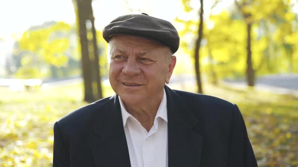 Portrait of a Fascinated Senior Man in a Cap Looking at One Point in Park