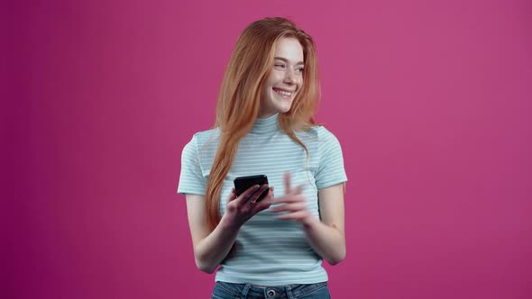 The Beautiful and Redhaired Teenager Reacts to the Message with a Wide Smile and Points Amusedly