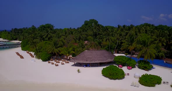 Daytime birds eye abstract shot of a sandy white paradise beach and turquoise sea background in 4K