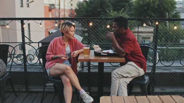 Multiethnic Couple Chatting at Outdoor Rooftop Bar