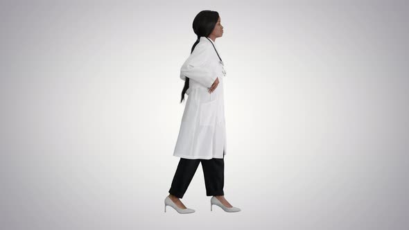 Sad African American Female Doctor Walking with Hands in Her Pockets on Gradient Background