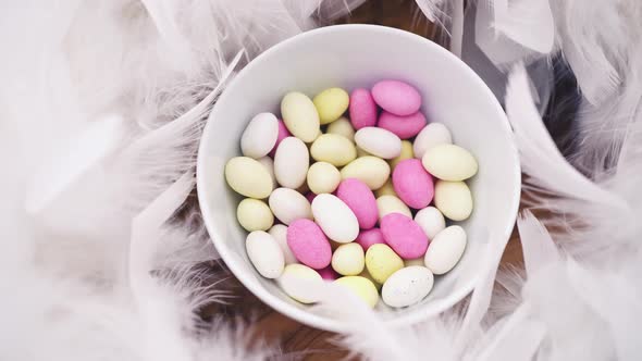 small pastel easter egg candy in a bowl with white feathers turning slowly