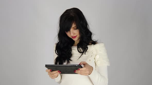 Portrait of a Laughing Woman Using Tablet Computer Isolated on a Gray Background, Looking at Camera