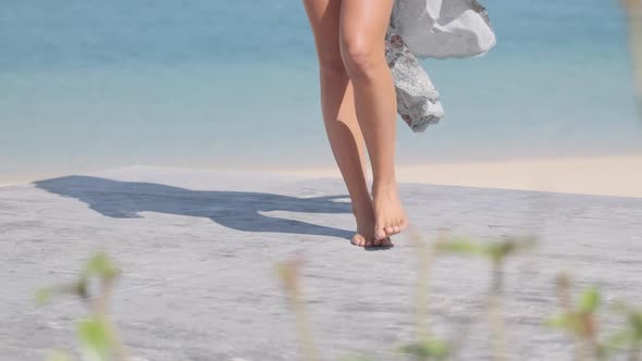 Legs of a Young Brunette in a Bikini Standing Along the Shore