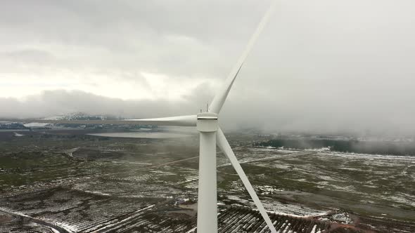 Wind turbine in a snowy landscape with early winter morning mist.