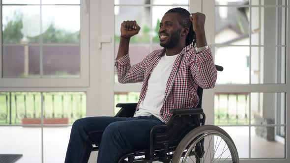 Excited Disabled African American Man in Wheelchair Gesturing Victory in Slow Motion Smiling