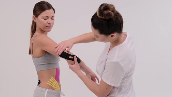 A female physiotherapist is measuring a piece of kinesiotape to be applied on a shoulder joint