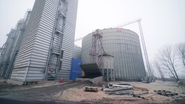 Metal tanks of elevator. Grain-drying complex outdoors. Commercial grain silos on sky background.