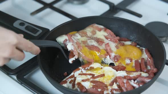 Sausage with eggs in a pan.