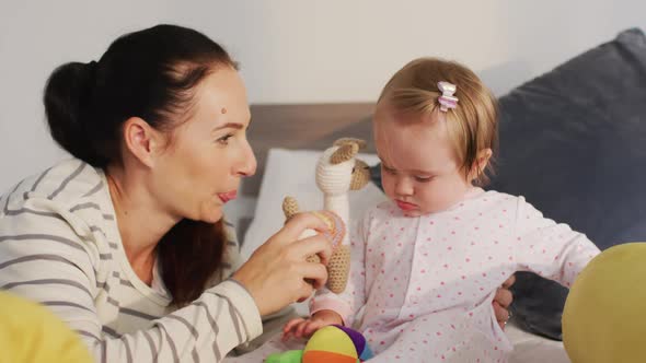 Caucasian mother and baby playing with toys on the bed at home