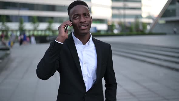 Young guy in a suit walks through the downtown and talks on the phone