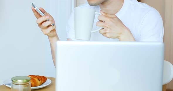 Man using mobile phone while having coffee 