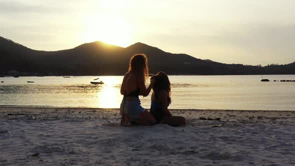 Pretty smiling ladies relaxing having fun on the beach on summer white sand and blue 4K background