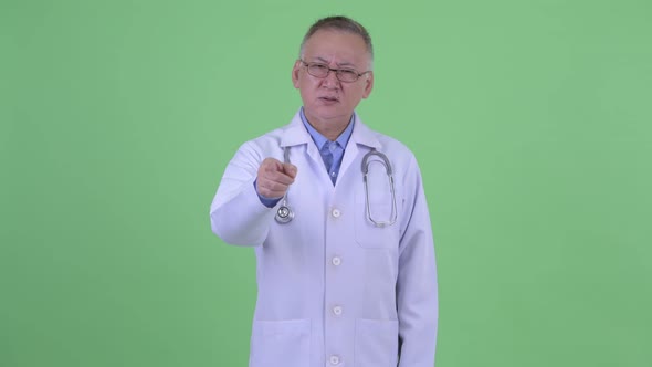 Sad Mature Japanese Man Doctor Pointing at Camera