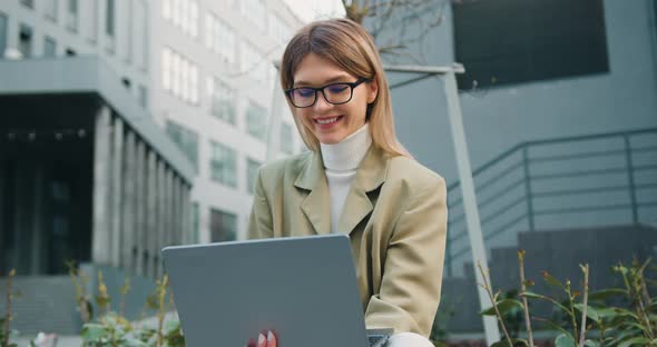 Woman Freelancer Working with Laptop in City on Modern urban street.