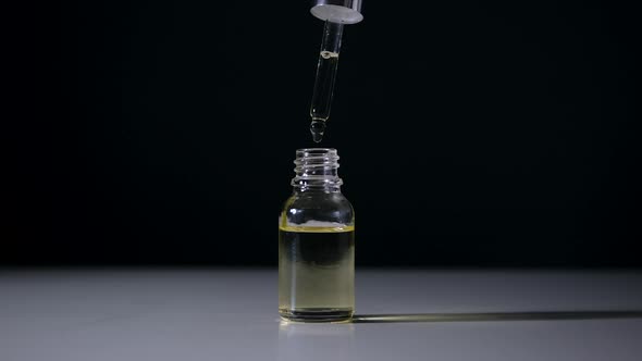 Bottle with Serum and Pipette on Black Background Closeup