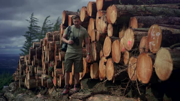 Hiker walking on tree trunk at stack of wood