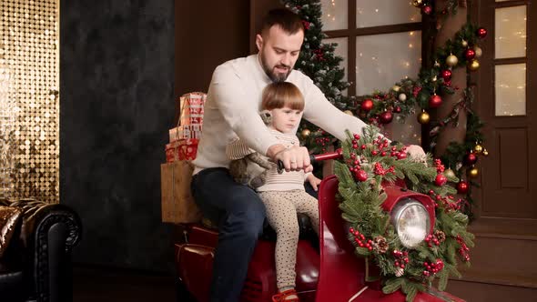 Child with Dad In the New Year's Interior are Sitting on a Moped on the Background of Bright Festive