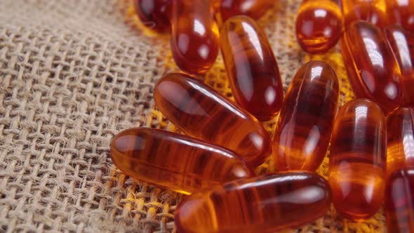 Fish oil omega 3 pills. Supplement medicinal orange gold capsules on a rough rustic burlap. Macro