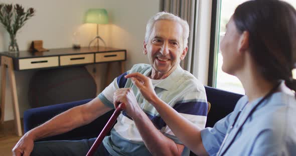 Animation of happy caucasian senior man with walking stick talking with biracial female doctor