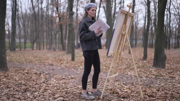 Wide Shot Focused Talented Young Woman Walking to Easel in Autumn Park Making Strokes on Canvas with