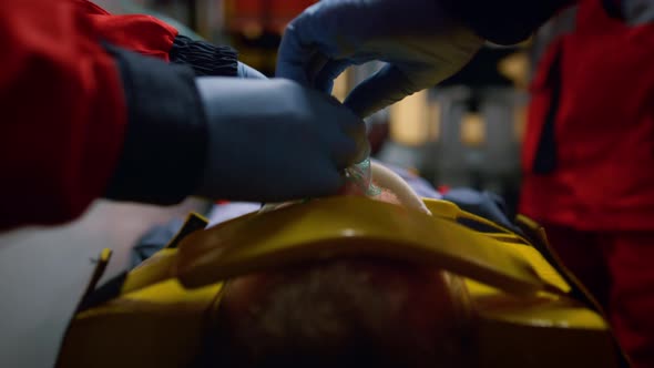 Team of Paramedics in Gloves Giving First Aid Help to Patient in Ambulance Car