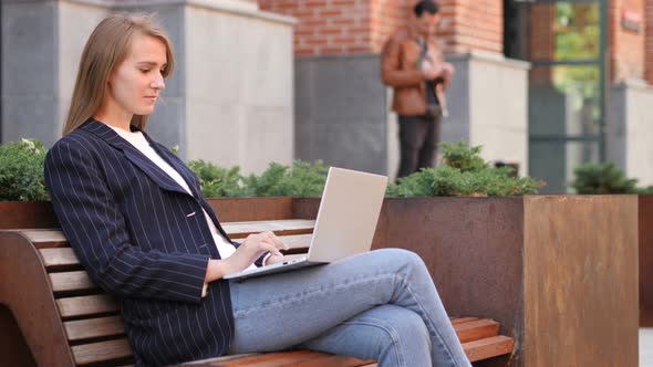 Businesswoman Working on Laptop while Sitting Outside Office