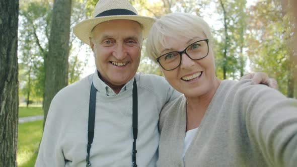 POV Portrait of Cheerful Couple Senior People Making Online Video Call From Park Looking at Camera