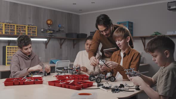 Teacher Helping Students With Robotic Models alt