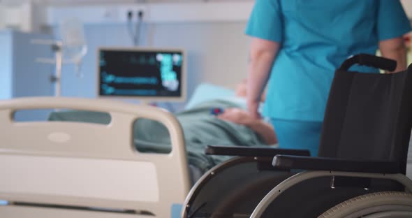 Cropped Shot of Nurse Taking Care of Disabled Elderly Woman Lying in Medical Bed