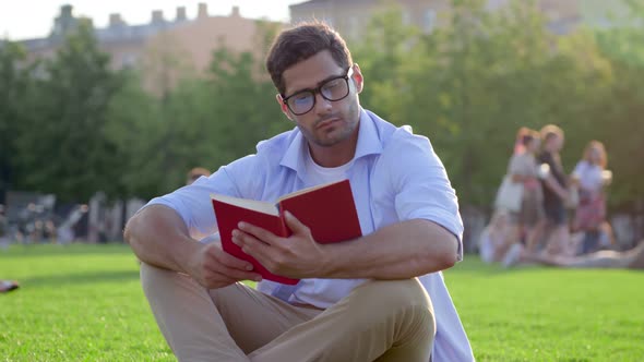 Young Indian Man Reading Book on Green Grass in Park