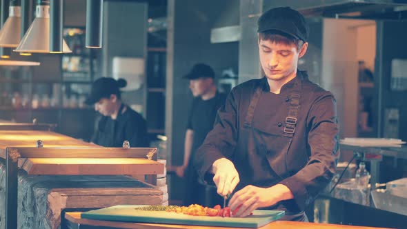 A Cook is Cutting Vegetables on the Chopping Board