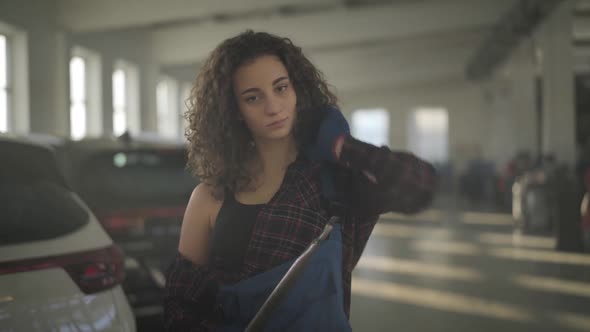 Portrait of Confident Young Caucasian Woman Posing in Auto Repair Shop with Wrench. Attractive