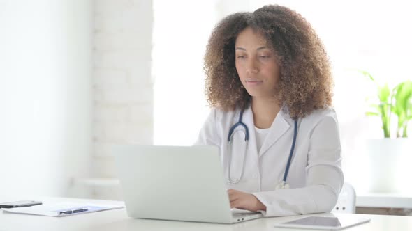 Afrcian Doctor Looking at Camera while using Laptop in Clinic