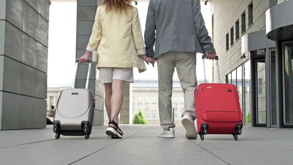 Couple with Suitcases Walking Through the Airport or Train Station