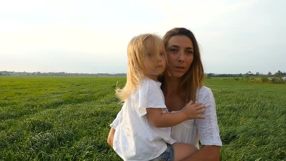 Happy Mother and Her Little Daughter Walk on The Green Grass