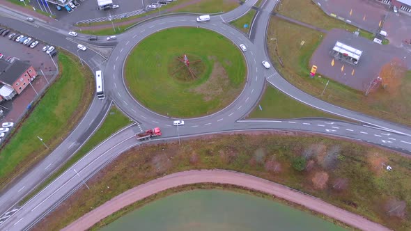 Rotating drone footage of a roundabout with with cars driving in and out of it, on a cloudy day in O