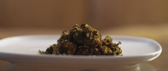 Plate with cannabis buds being moved on a table,close up,shallow depth of field