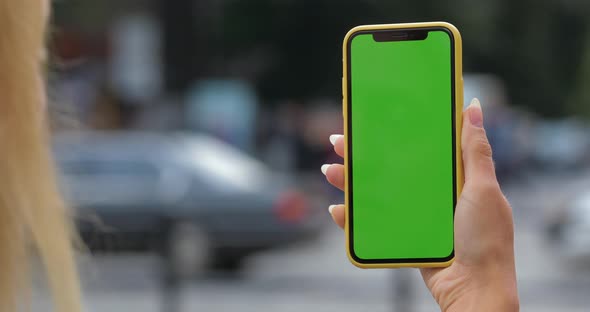 Overshoulder View of Blond Hair Woman Holding and Looking at Mock Up Smartphone. Crop View of Female