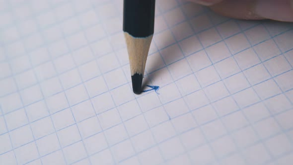 Person Draws and Breaks Pencil Slate on Paper Macro