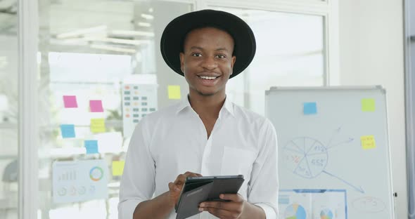 African American in Black Hat and White Shirt Looking Into Camera in Contemporary Glass Office