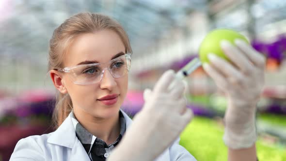 Female Biology Researcher Testing Useful Composition in Green Apple Using Syringe Closeup