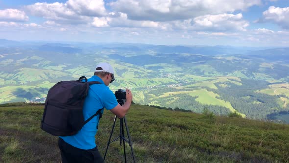 A man photographs a mountain landscape while hiking in the mountains.