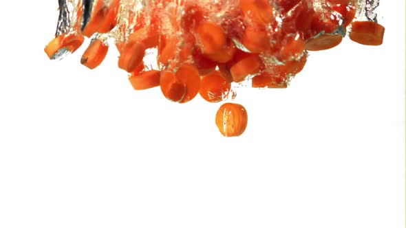 Super Slow Motion Pieces of Fresh Carrots Fall Under the Water with Air Bubbles