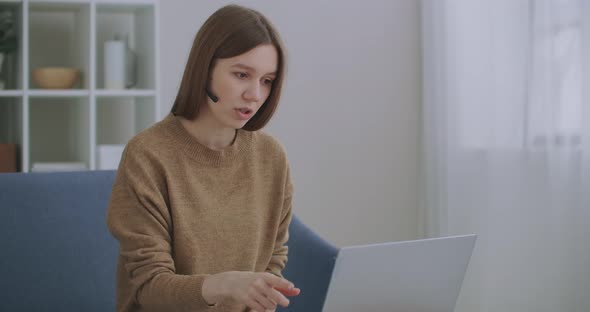 Woman Is Communicating Online, Using Laptop with Internet and Headphones with Microphone, Online