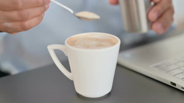 Close Up of Hands of Businessman Adding Sugar in Coffee