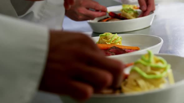 Close-up of team of chefs garnishing dishes